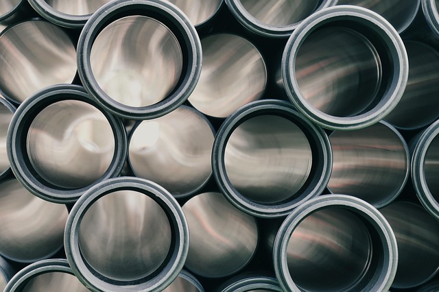Quality control inspector examining a batch of HDPE pipe fittings under bright inspection lighting in a clean quality assurance area with certification documents on clipboard